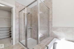 Bathroom featuring a glass-enclosed shower, tiled walls and flooring, and a portion of a white bathtub - 