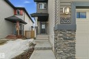 The property features a stone column accent with a wall-mounted outdoor light fixture and clear house numbering - 3235 Abbott Crescent, Edmonton, AB  - Outdoor 