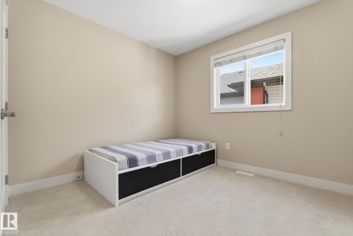 The room features neutral-toned walls, light-colored carpeting, and a window providing natural light - 3235 Abbott Crescent, Edmonton, AB - Indoor Photo Showing Bedroom