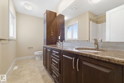 Bathroom featuring a dark wood vanity with a granite countertop and a chrome faucet - 