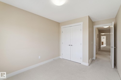 This room features neutral-toned walls, light-colored carpeting, and a white ceiling with a flush-mount light fixture - 3235 Abbott Crescent, Edmonton, AB - Indoor Photo Showing Other Room