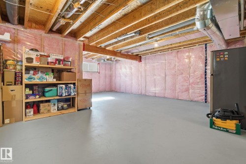 The property features exposed wooden ceiling beams and a painted concrete floor, with a window providing natural light - 3235 Abbott Crescent, Edmonton, AB - Indoor Photo Showing Basement