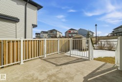 The property features a concrete patio with white railings and a partial wood fence - 