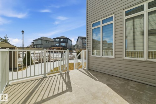 The property features an outdoor patio area with white railings, offering views of a fenced yard and mature trees - 3235 Abbott Crescent, Edmonton, AB - Outdoor With Deck Patio Veranda