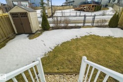 The property features a backyard with a lawn, a storage shed, and a wooden fence - 