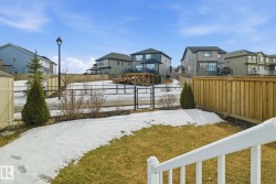 The property features a spacious yard with a lawn and a black chain link fence - 