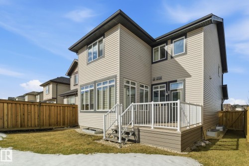 The property features a two-story exterior with light-colored siding, a dark roof, and white-framed windows - 3235 Abbott Crescent, Edmonton, AB - Outdoor With Deck Patio Veranda