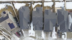 Overhead view of several residential properties, each featuring a private driveway and a shingled roof - 