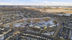 Aerial view of a residential area featuring a large building with a colorful facade, surrounded by other properties and open land - 