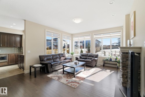 The living area features hardwood floors and large windows providing natural light - 3235 Abbott Crescent, Edmonton, AB - Indoor Photo Showing Living Room With Fireplace