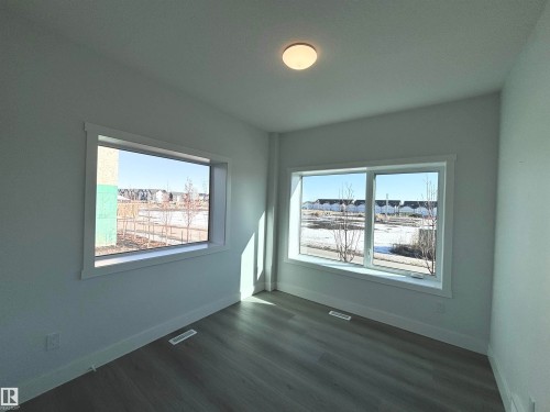 This room features light-colored walls, recessed ceiling lighting, and two large windows offering views of the exterior - 2740 Blatchford Road, Edmonton, AB - Indoor Photo Showing Other Room