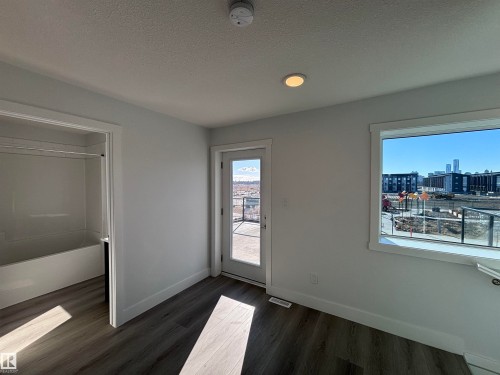This bright room features durable flooring, a window offering city views, and a door leading to an outdoor space - 2740 Blatchford Road, Edmonton, AB - Indoor Photo Showing Other Room