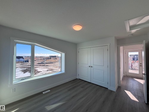 This room features a distinctively angled window, a double-door closet, and durable flooring, with a visible door leading to an outdoor space - 2740 Blatchford Road, Edmonton, AB - Indoor Photo Showing Other Room