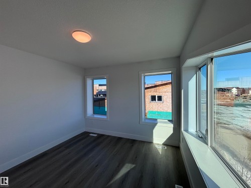 This room features a ceiling light fixture, three windows providing natural light, and modern flooring - 2740 Blatchford Road, Edmonton, AB - Indoor Photo Showing Other Room