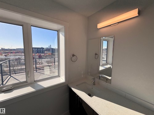 The bathroom features a window providing natural light, a vanity with a white countertop and integrated sink, a wall-mounted mirror, and an overhead light fixture - 2740 Blatchford Road, Edmonton, AB - Indoor Photo Showing Other Room