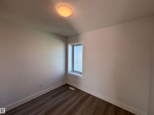 This room features light-colored walls, a window with white trim, and wood-look flooring - 2740 Blatchford Road, Edmonton, AB - Indoor Photo Showing Other Room