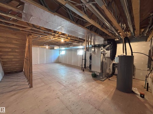 The property features an unfinished basement with exposed wooden beams, a water heater, and a furnace system - 2740 Blatchford Road, Edmonton, AB - Indoor Photo Showing Basement