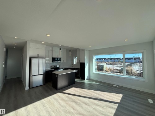 Open concept living area with light-toned flooring, recessed lighting, and a large window offering expansive views - 2740 Blatchford Road, Edmonton, AB - Indoor