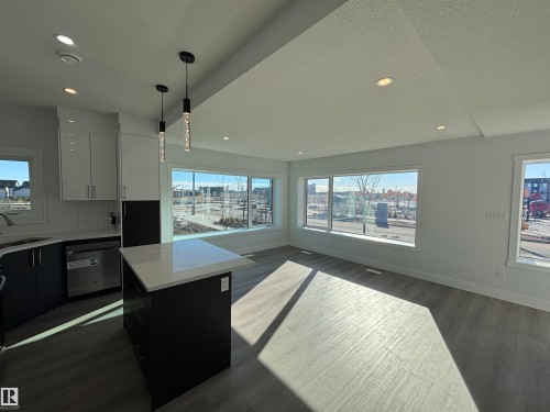 This bright and airy space features an open concept layout with large windows, recessed lighting, and a kitchen island with a white countertop and pendant lighting - 2740 Blatchford Road, Edmonton, AB - Indoor Photo Showing Kitchen