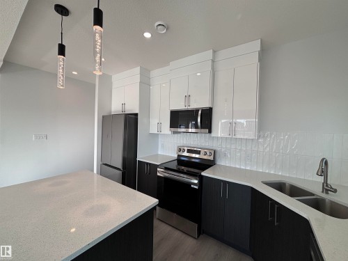 The kitchen features modern two-tone cabinetry, stainless steel appliances, white subway tile backsplash, and light-colored countertops - 2740 Blatchford Road, Edmonton, AB - Indoor Photo Showing Kitchen With Double Sink With Upgraded Kitchen