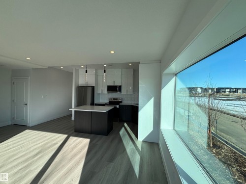 Open concept living area with light-toned flooring and a large window providing views of the surrounding area - 2740 Blatchford Road, Edmonton, AB - Indoor