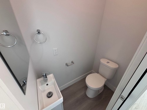 The bathroom features light gray walls, a white toilet, a modern rectangular sink with a chrome faucet, and wood-look flooring - 2740 Blatchford Road, Edmonton, AB - Indoor Photo Showing Bathroom