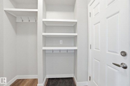 Entryway area featuring built-in shelving, wall hooks, and a paneled door with a brushed nickel handle - 1607 202 Street, Edmonton, AB - Indoor With Storage