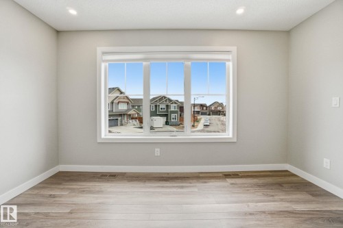 This room features light-colored walls and wood-style flooring, creating a bright and inviting atmosphere - 1607 202 Street, Edmonton, AB - Indoor Photo Showing Other Room