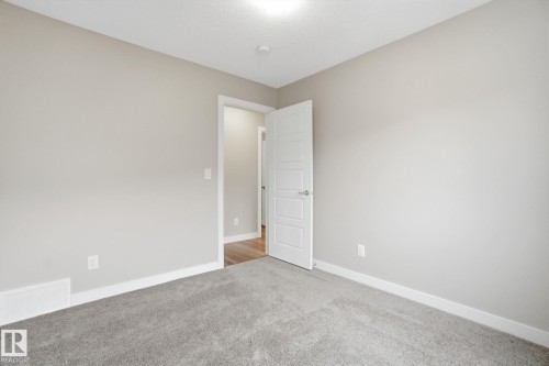 This room features light grey carpeting, light grey walls, white trim, and a white interior door - 1607 202 Street, Edmonton, AB - Indoor Photo Showing Other Room