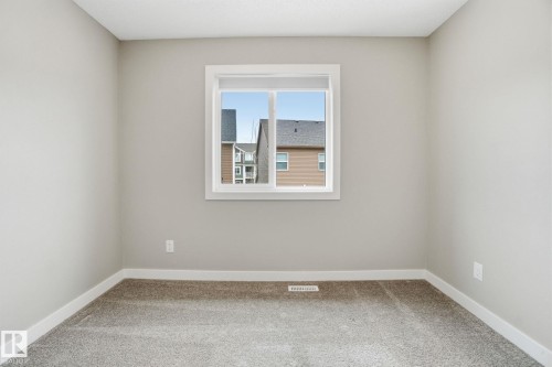 The room features neutral-toned walls, a window with white trim, and light grey carpet flooring - 1607 202 Street, Edmonton, AB - Indoor Photo Showing Other Room