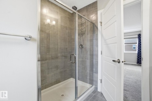 This shower features a glass enclosure, grey tile walls, and chrome fixtures - 1607 202 Street, Edmonton, AB - Indoor Photo Showing Bathroom