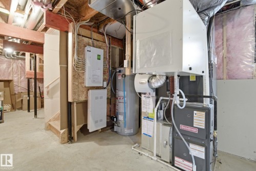 The utility area features a water heater, furnace, and electrical panels, all situated on a concrete floor - 1607 202 Street, Edmonton, AB - Indoor Photo Showing Basement