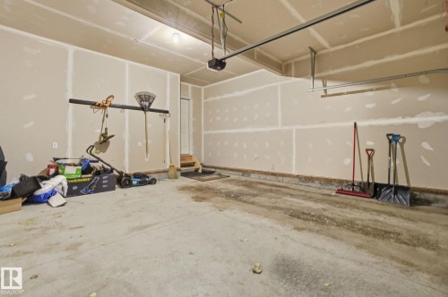 The property features an attached garage with unfinished walls, a concrete floor, and overhead garage door tracks - 1607 202 Street, Edmonton, AB - Indoor Photo Showing Garage