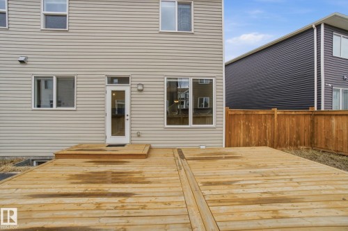 The property features a spacious wooden deck with direct access to the interior via a glass-paneled door - 1607 202 Street, Edmonton, AB - Outdoor With Exterior
