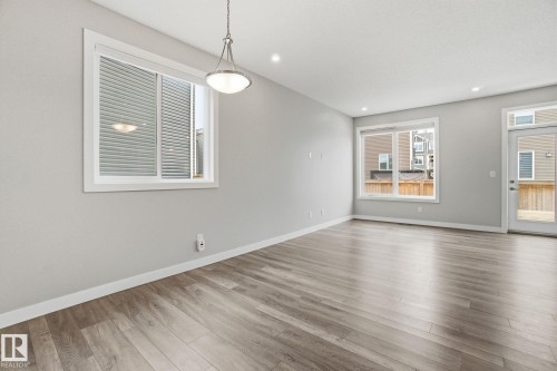 Bright interior space featuring light-colored walls, recessed ceiling lighting, and a modern light fixture - 1607 202 Street, Edmonton, AB - Indoor Photo Showing Living Room