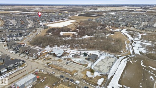 Aerial view highlighting the surrounding community, including residential homes, natural areas with trees, and a pond - 1607 202 Street, Edmonton, AB - Outdoor With View