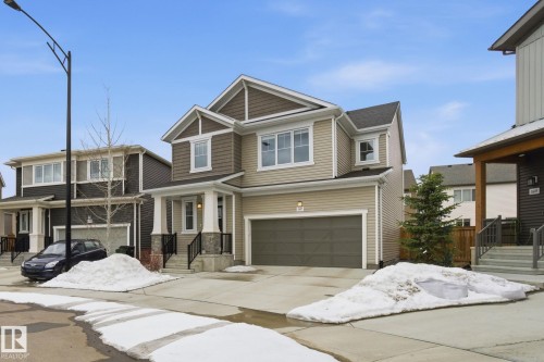 The property features a two-story design with light-colored siding and a contrasting darker siding on the upper level - 1607 202 Street, Edmonton, AB - Outdoor With Facade