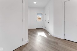 Entryway featuring light wood-look flooring, white walls, and a modern ceiling light fixture - 