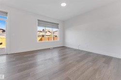 This bright room features light-colored flooring, white walls, and a large window with blinds - 