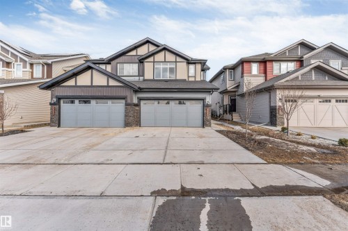 The property features a concrete driveway and two attached garages with light grey doors, offering ample parking - 1663 Cavanagh Boulevard Sw, Edmonton, AB - Outdoor With Facade