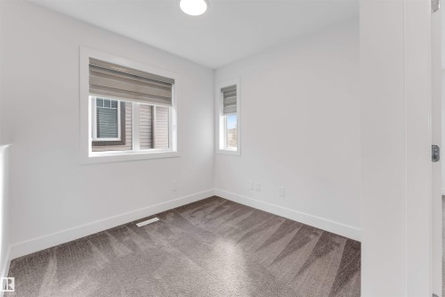 This room features white walls, two windows with blinds, and patterned carpeting - 1663 Cavanagh Boulevard Sw, Edmonton, AB - Indoor Photo Showing Other Room