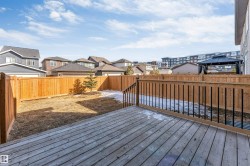 The property features a spacious wooden deck with railings, overlooking a fenced yard - 