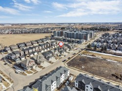 An aerial view of the property's neighborhood, showcasing residential streets, detached homes, and a larger apartment building in the surrounding area - 
