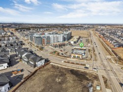 Aerial view showcasing a developed neighborhood with residential properties, commercial buildings, and a major roadway - 