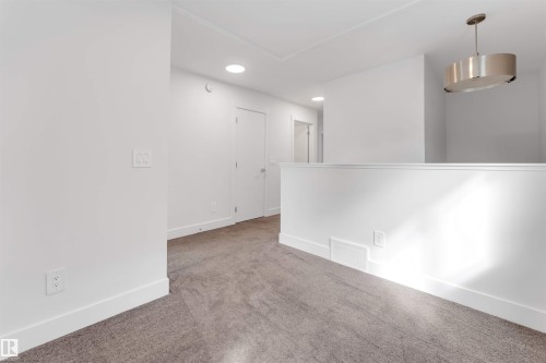 This area features neutral tone carpet, white walls, and recessed lighting - 1663 Cavanagh Boulevard Sw, Edmonton, AB - Indoor Photo Showing Other Room