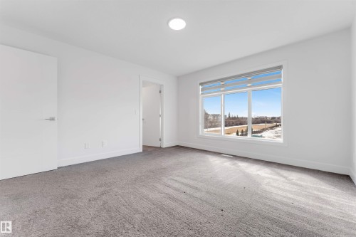 This room features light gray carpeting, white walls, and a large window with horizontal blinds - 1663 Cavanagh Boulevard Sw, Edmonton, AB - Indoor Photo Showing Other Room