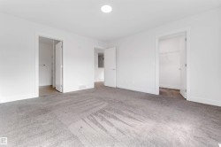 The property features a spacious room with light grey carpeting, white walls, and white trim - 
