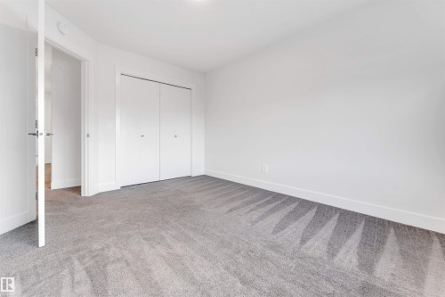 This room features neutral-toned carpet flooring, white walls, and a closet with bifold doors - 1663 Cavanagh Boulevard Sw, Edmonton, AB - Indoor Photo Showing Other Room