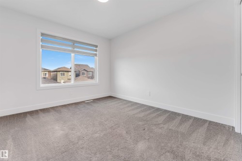 This room features a window with blinds, carpeted flooring, and white walls - 1663 Cavanagh Boulevard Sw, Edmonton, AB - Indoor Photo Showing Other Room