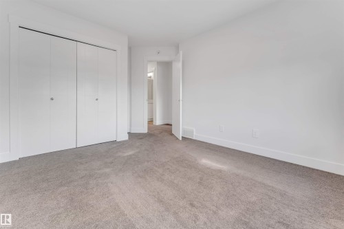This room features light gray carpeting, white walls, and white bi-fold closet doors - 1663 Cavanagh Boulevard Sw, Edmonton, AB - Indoor Photo Showing Other Room